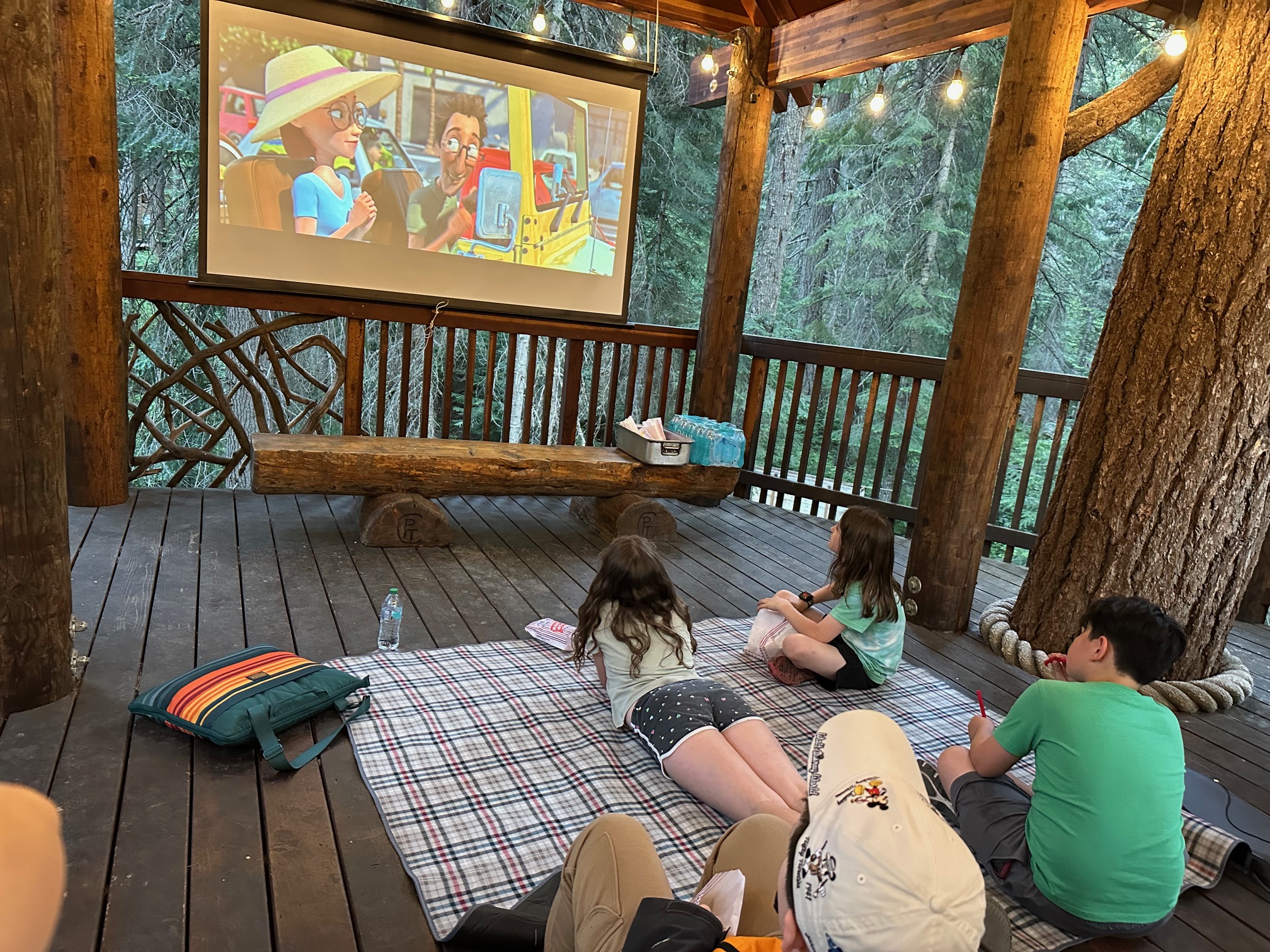 Children watching a movie on an log cabin deck