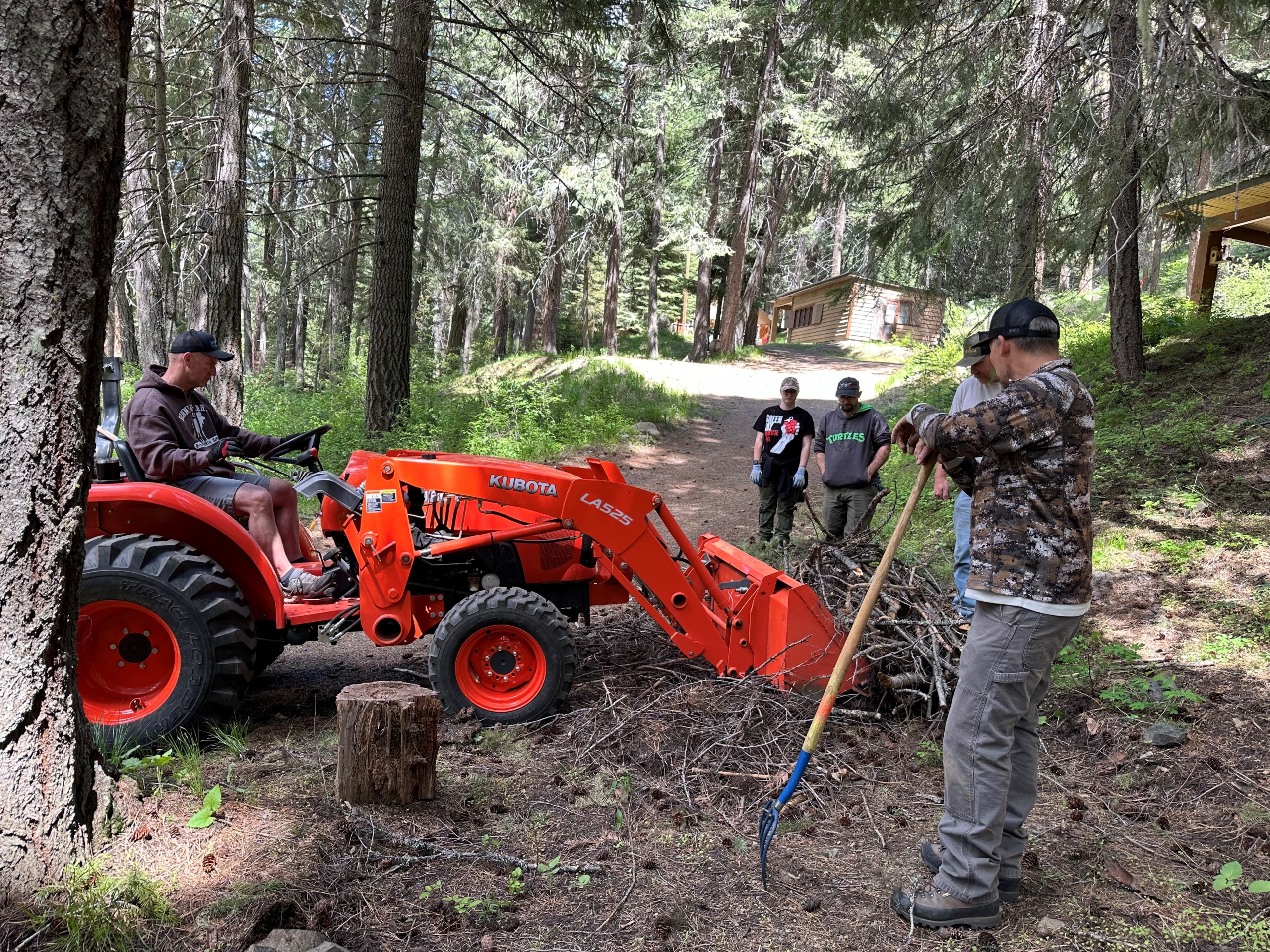A work party cleaning up a camp trail with a tractor